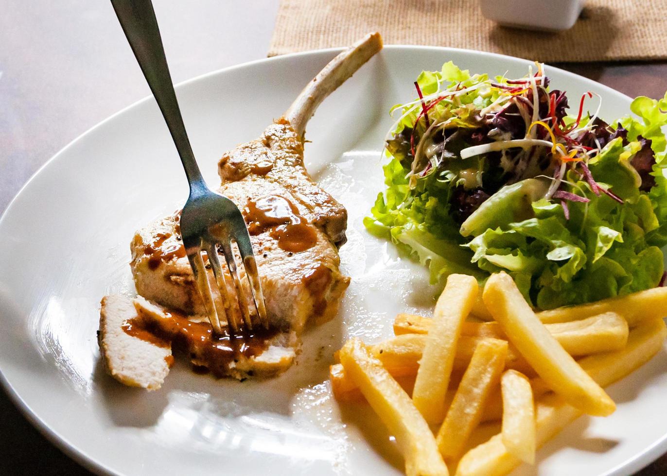 fläskkotlettstek med sallad och pommes frites foto