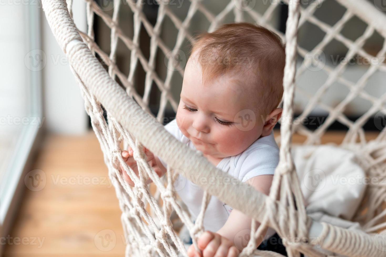 söt, liten, vacker tjej i en stickad stol-gunga foto