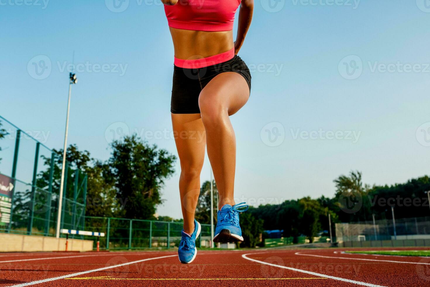 ung kvinna idrottare på startande placera redo till Start en lopp på racerbana. foto