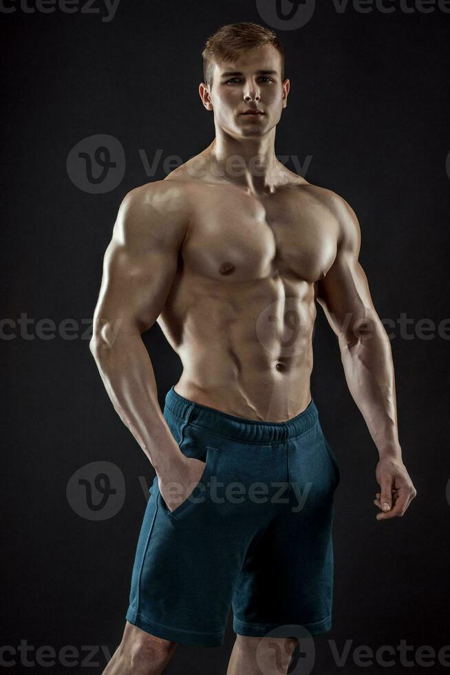 muskulös kroppsbyggare kille håller på med Framställ över svart bakgrund foto
