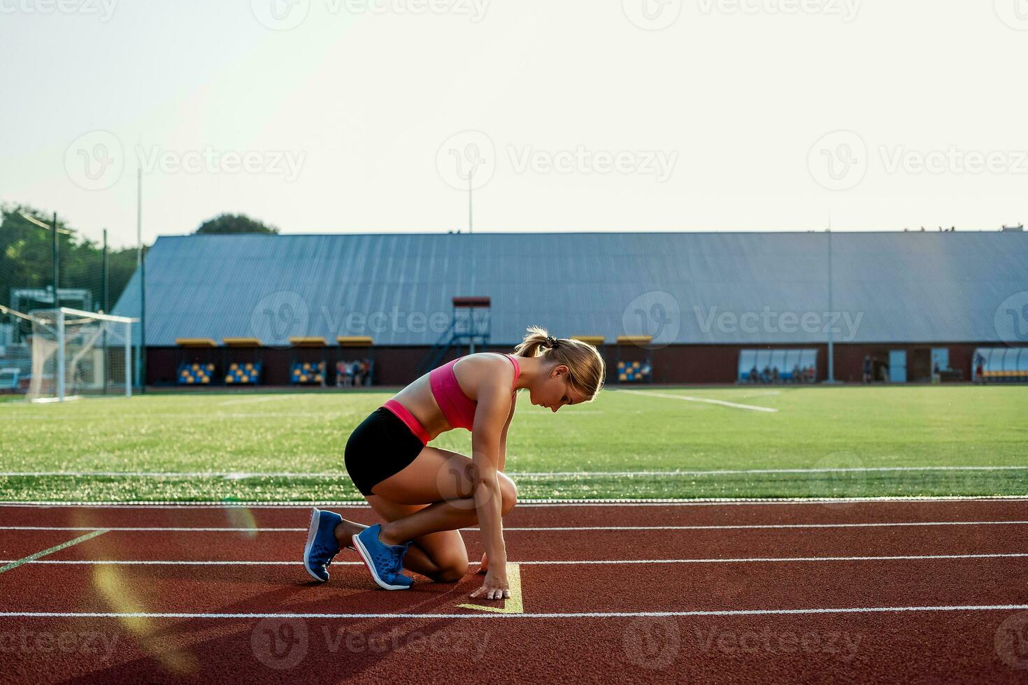 ung kvinna idrottare på startande placera redo till Start en lopp på racerbana. foto