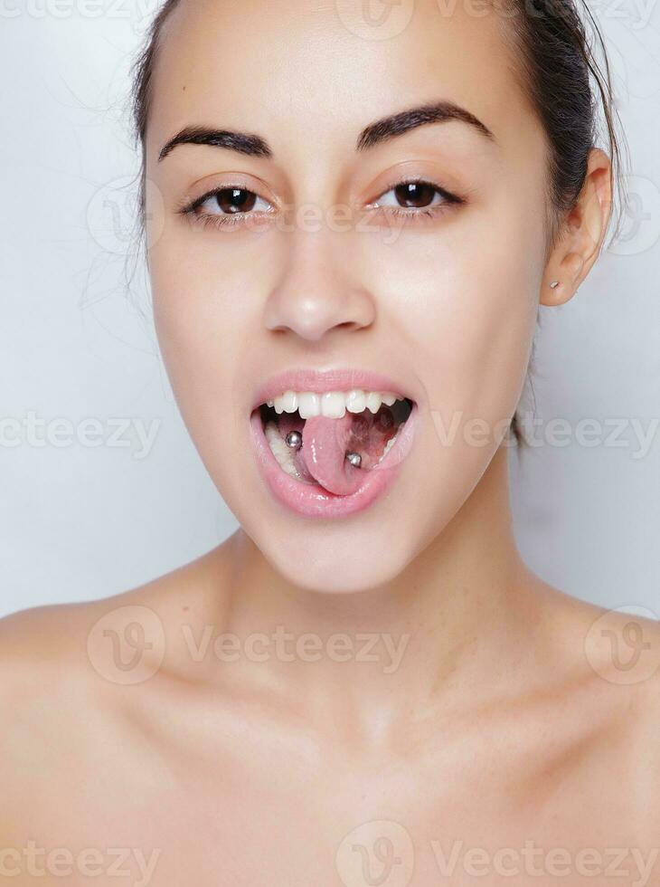 vacker kvinna sticker ut tungan och visar unga piercing foto