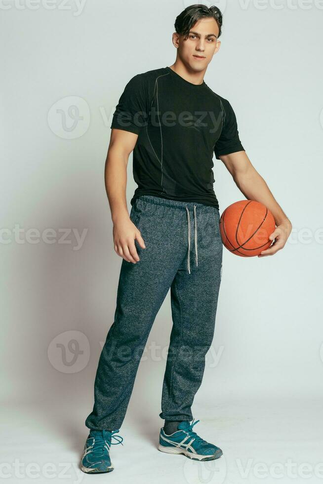 stilig ung leende man bärande en basketboll boll foto