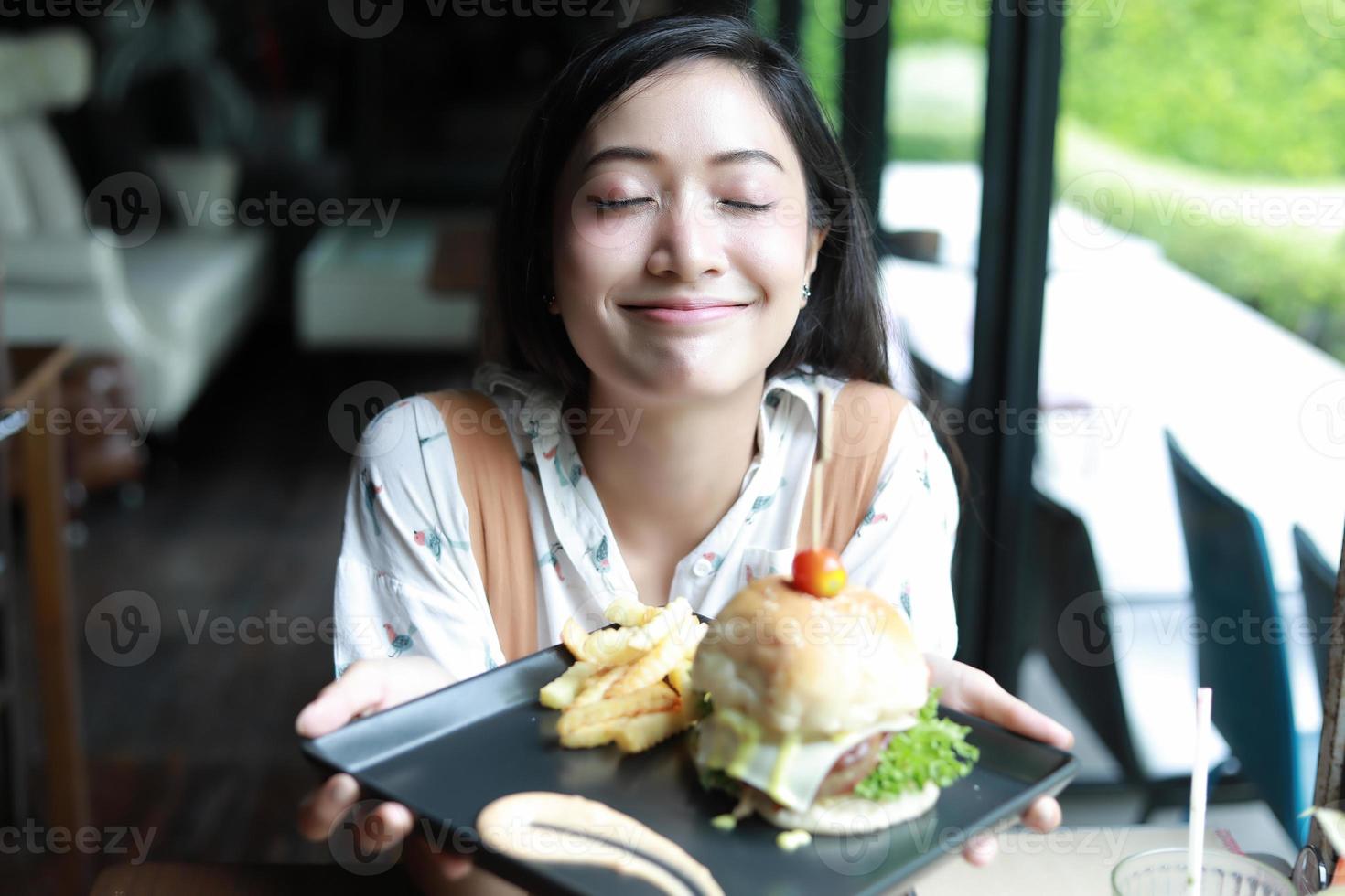 asiatiska kvinnor leende och glada och njöt av att äta hamburgare på kaffe och restaurang vid avkoppling foto