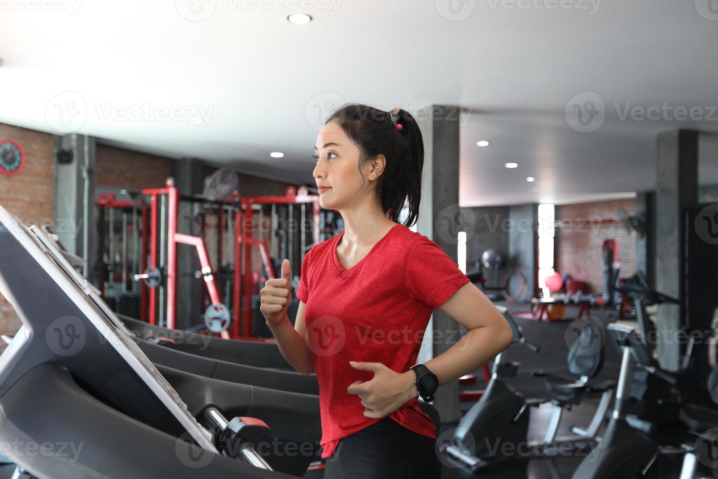 asiatiska kvinnor som kör sportskor på gymmet medan en ung kaukasisk kvinna joggar på löpbandet foto