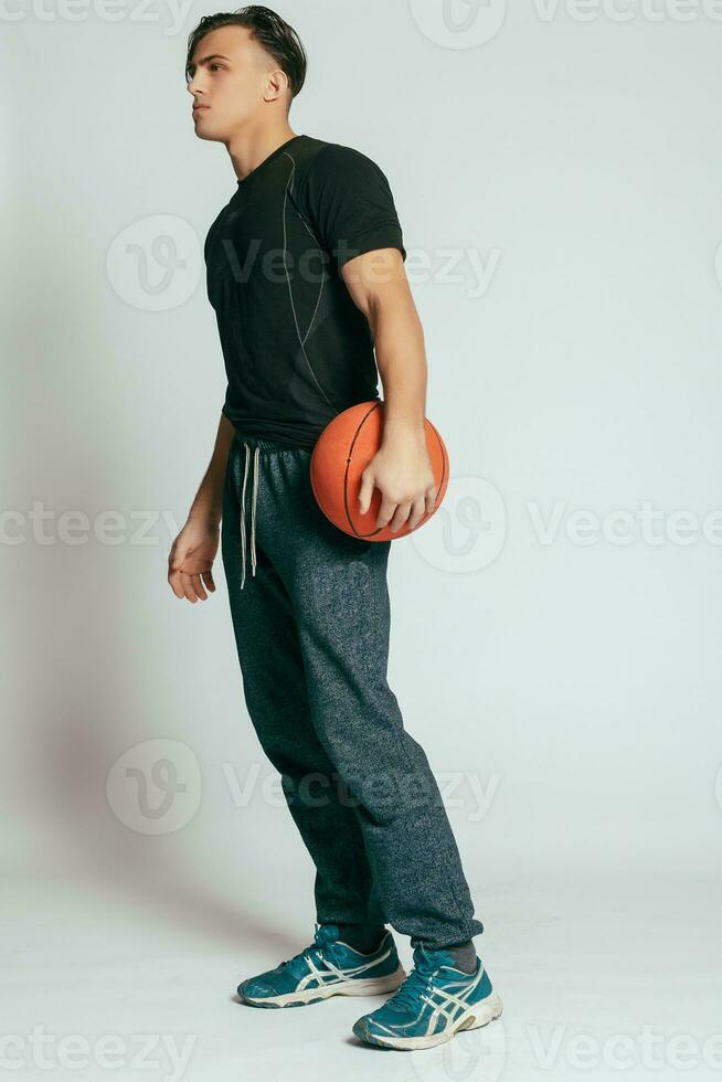 stilig ung leende man bärande en basketboll boll foto