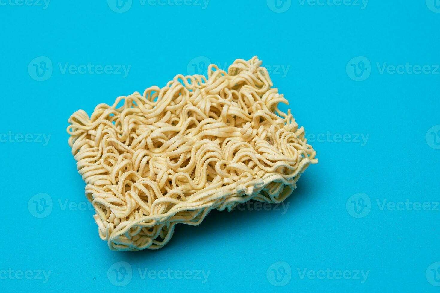 okokt omedelbar spaghetti på blå bakgrund. rå pasta. torr asiatisk snabb mat. snabbt lunch foto