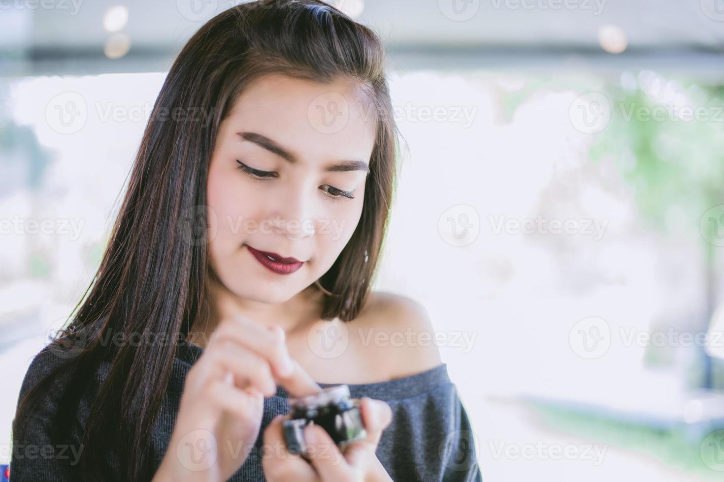 en vacker asiatisk kvinna som använder en hudvårdsprodukt, fuktkräm eller lotion som tar hand om hennes torra hy. fuktkräm i kvinnliga händer. foto