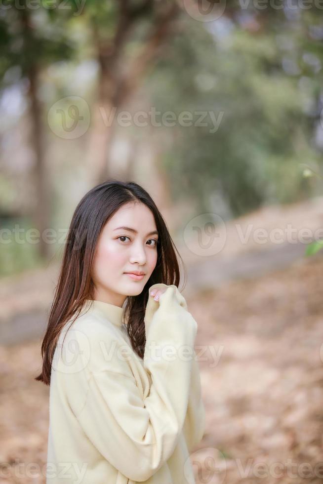 vacker asiatisk kvinna leende glad tjej och bär varma kläder vinter- och höstporträtt utomhus i parken foto