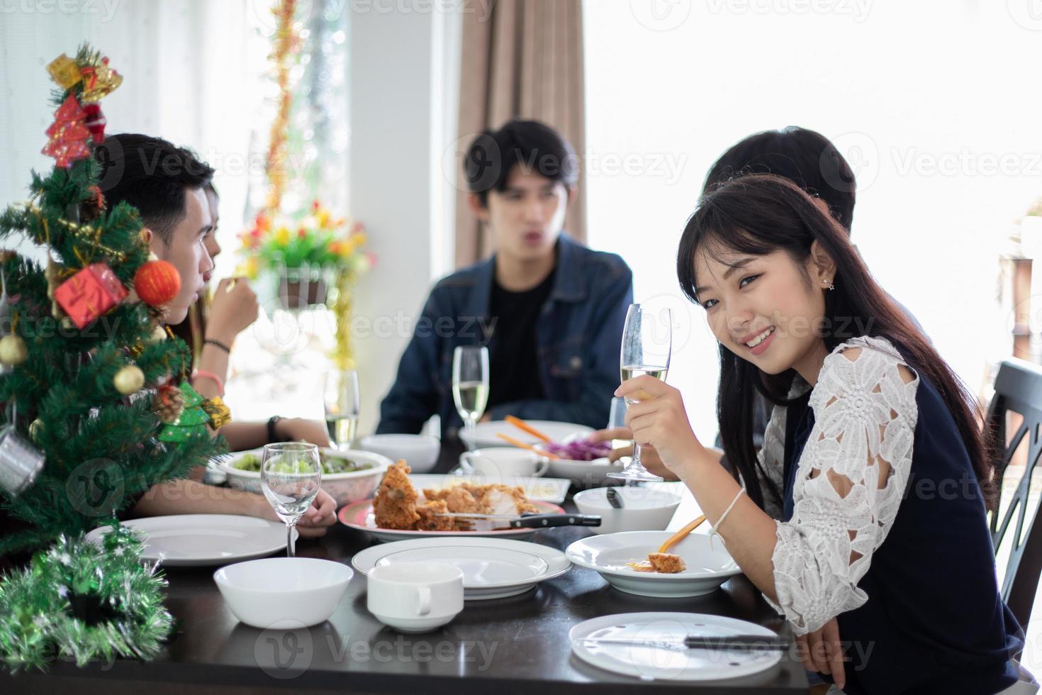 middag med asiatisk grupp bästa vänner som njuter av kvällsdrycker medan du sitter vid matbordet på köket tillsammans, mjukt fokus foto