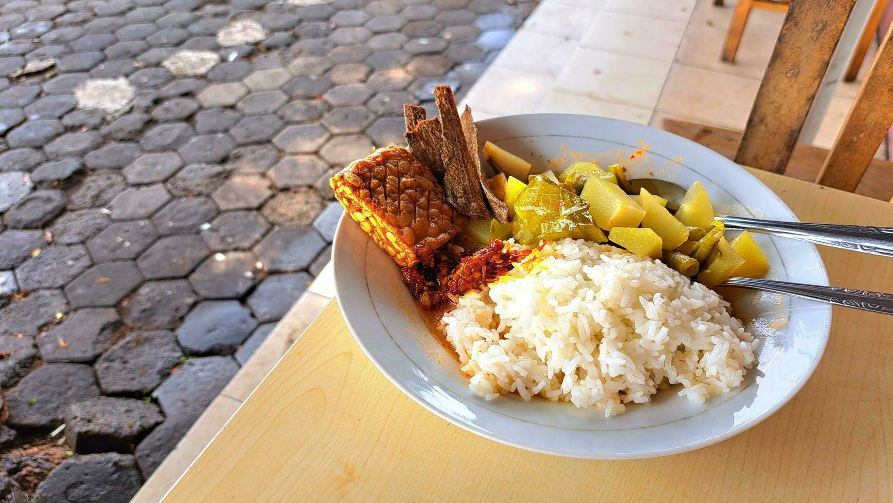 en tallrik av ris, tamarind grönsaker, chili sås, tempeh och saltade fisk på de tabell, lämplig för reklam typisk mat foto