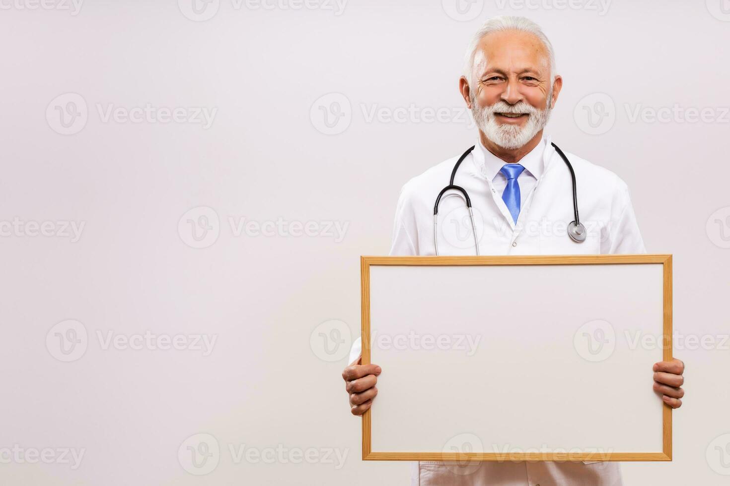 porträtt av senior läkare innehav whiteboard på grå bakgrund. foto