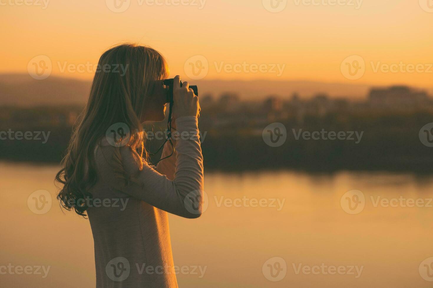 silhuett av en kvinna fotografering på de solnedgång. foto