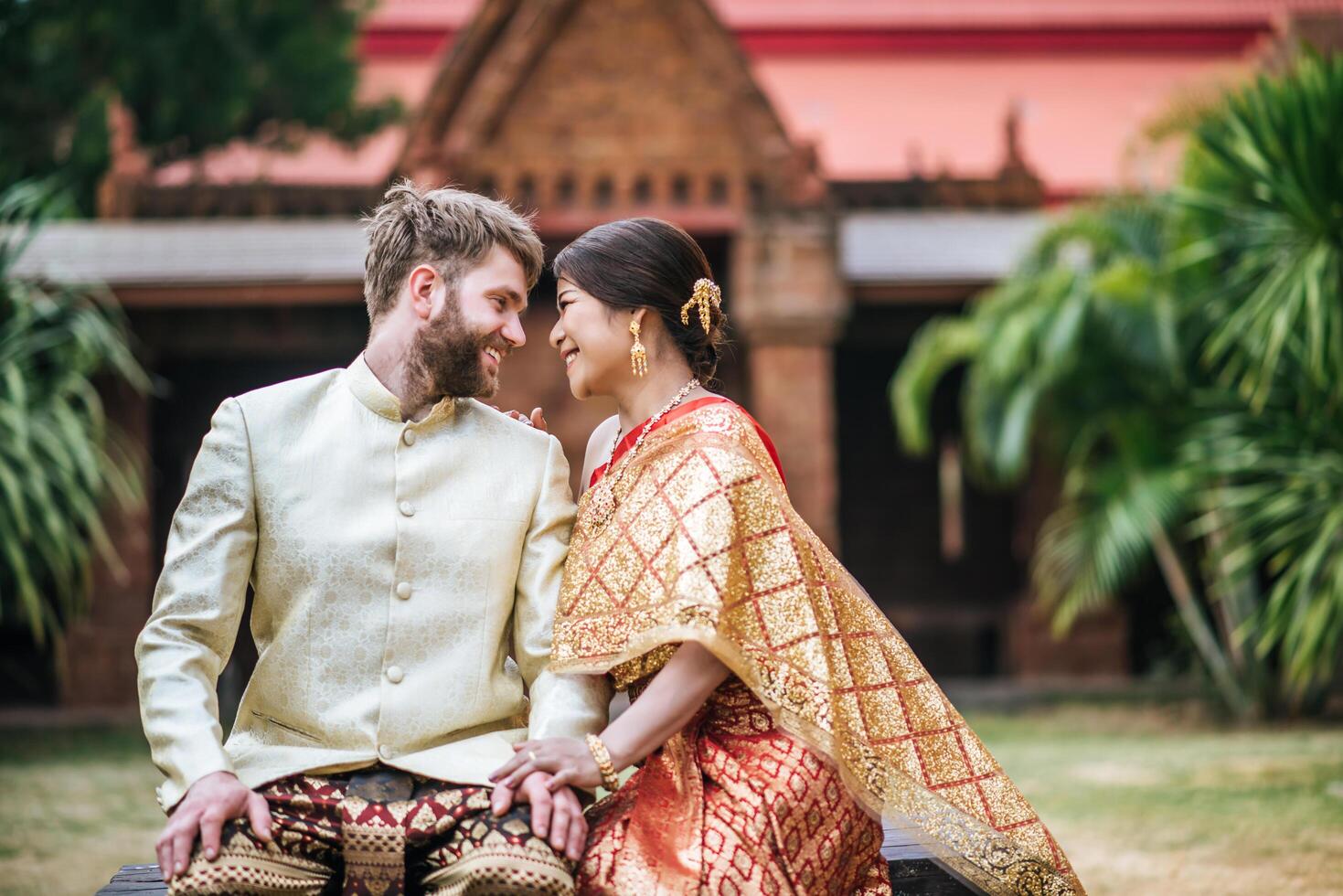 asiatisk brud och kaukasisk brudgum har romantisk tid med thailändsk klänning foto