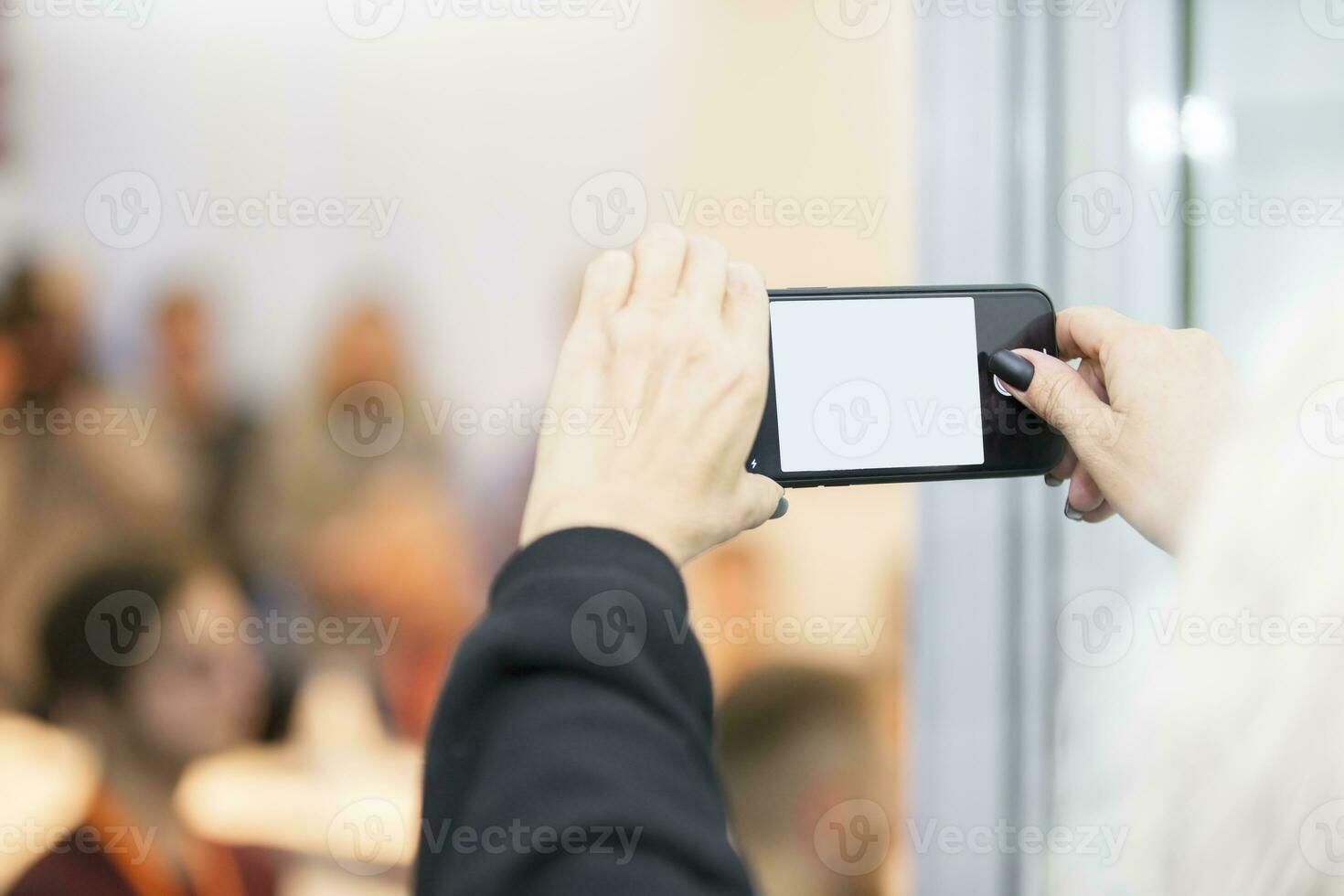 händer innehav smartphone med tömma skärm sv mot suddig människor bakgrund. foto