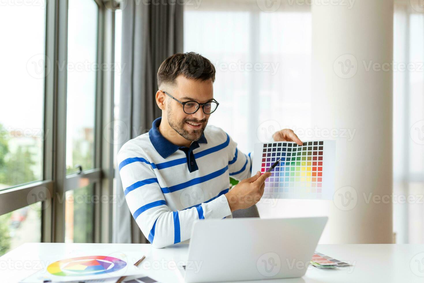 glad man designer har video konferens med kunder, Sammanträde på skrivbord i främre av dator, innehav Färg paletter, gestikulerar och leende, kopia Plats foto