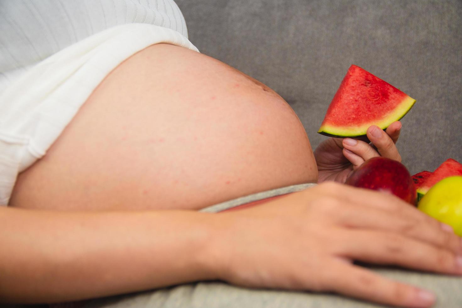gravid kvinna äter frukt vattenmelon äppeldruva foto