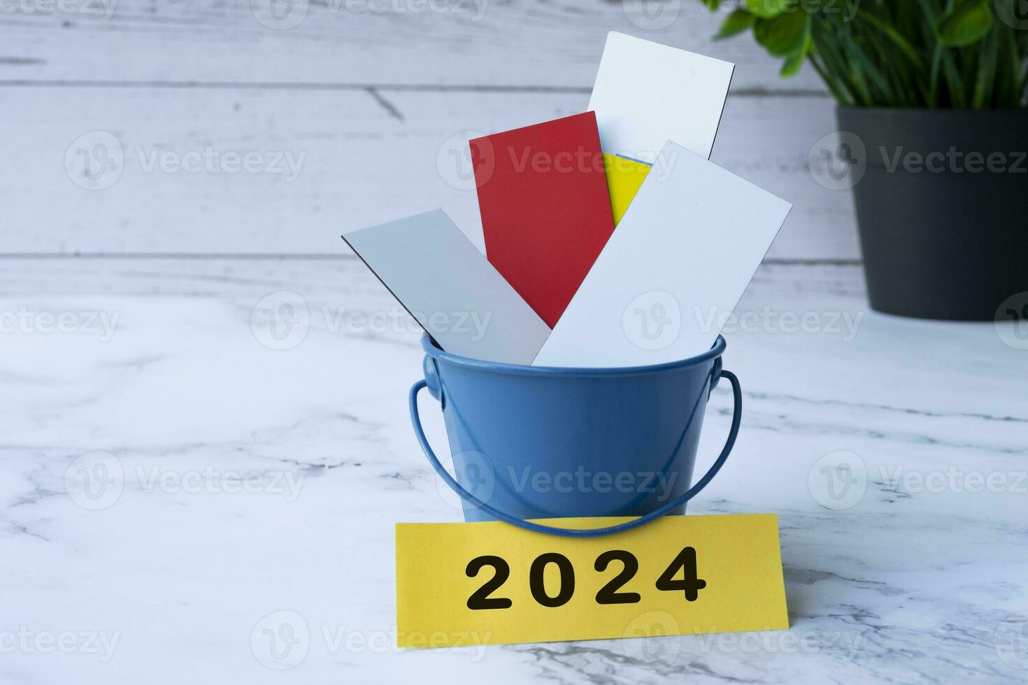färgrik papper inuti av en blå hink med 2024 märka. foto