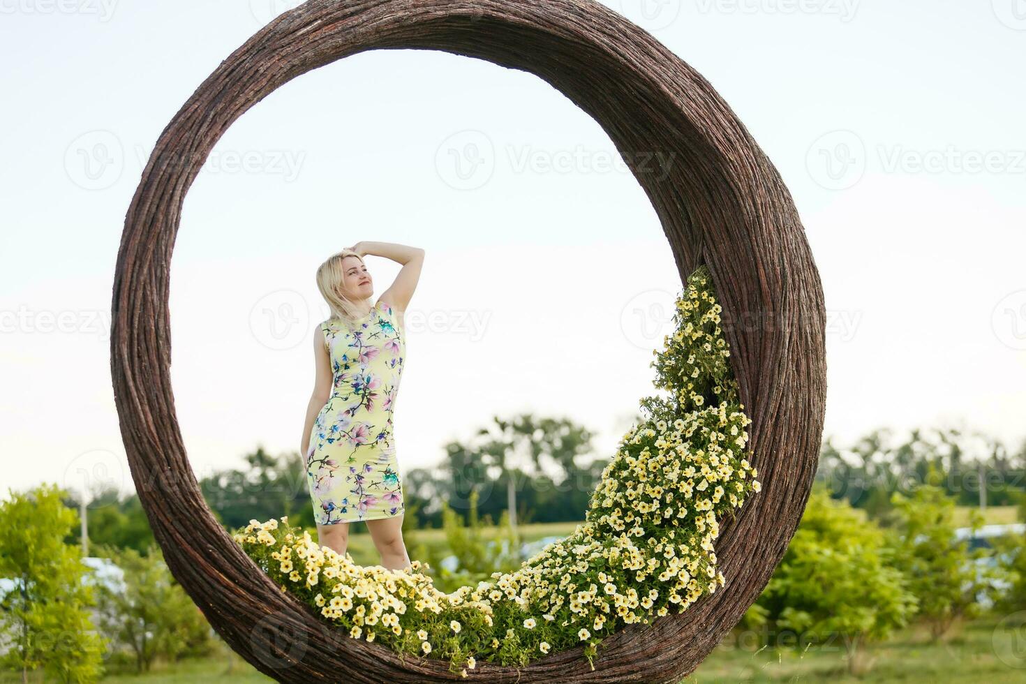 skön ung kvinna i trevlig klänning Framställ på färgrik vägg av blommor. mode Foto, trevlig hår, stor leende foto