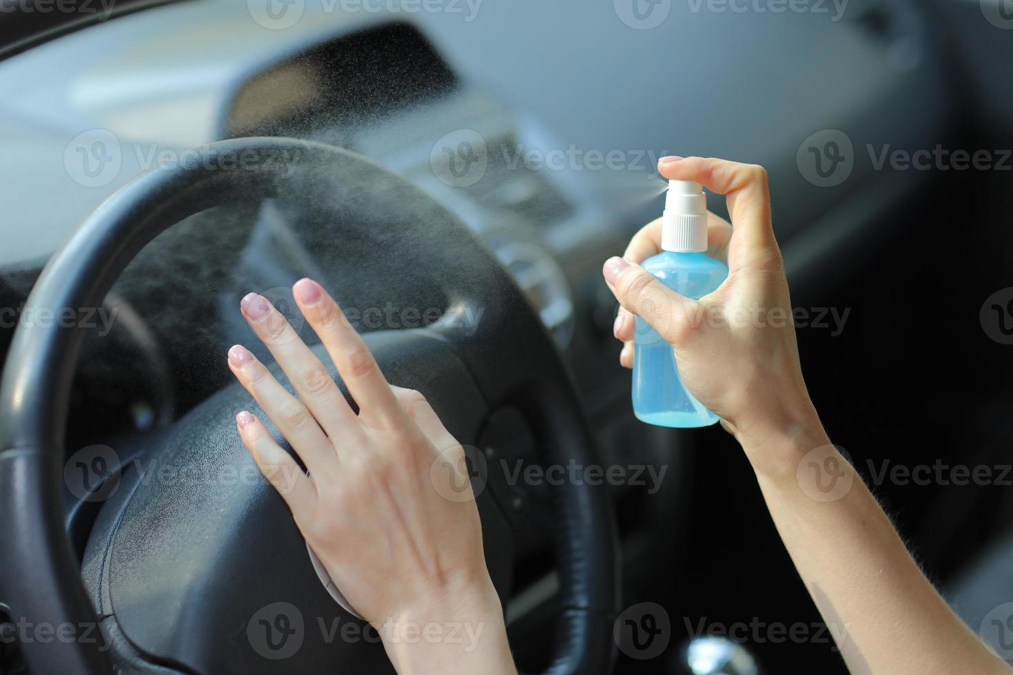 kvinnans hand sprutar alkohol, desinfektionsmedel i bilen, säkerhet, förhindrar infektion av covid 19-virus, koronavirus, förorening av bakterier eller bakterier. alkoholrenare, hygienkoncept. foto