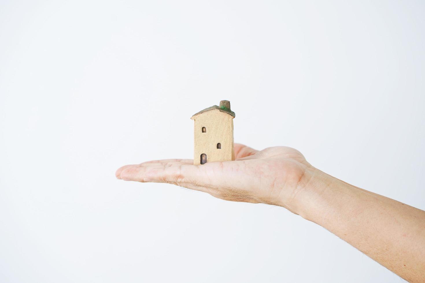 litet hus i mänskliga händer på en vit bakgrund foto