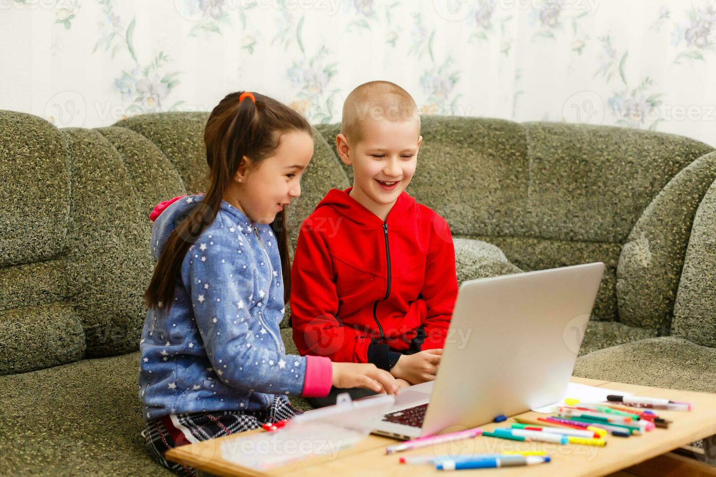 distans inlärning uppkopplad utbildning. skola pojke och flicka studerar på Hem med bärbar dator anteckningsbok och håller på med läxa. Sammanträde på en tabell foto