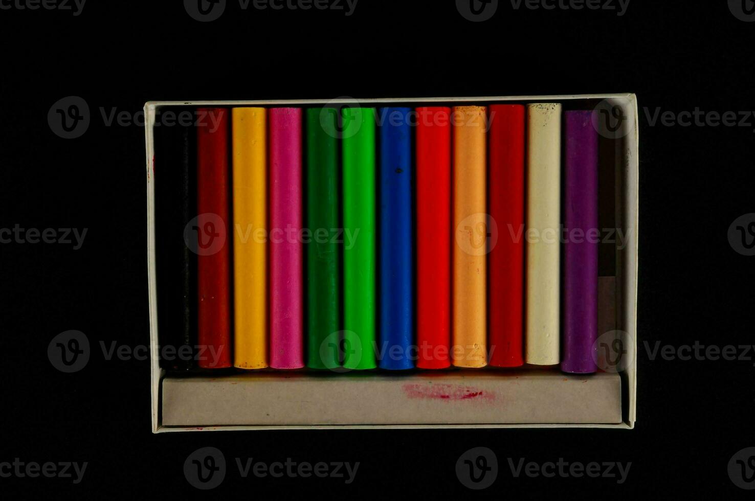 en låda av färgad pennor på en svart bakgrund foto