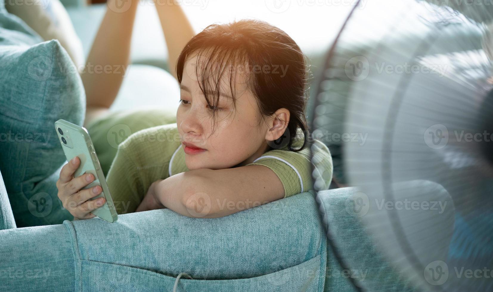 asiatisk tjej som ligger på soffan och använder telefonen foto