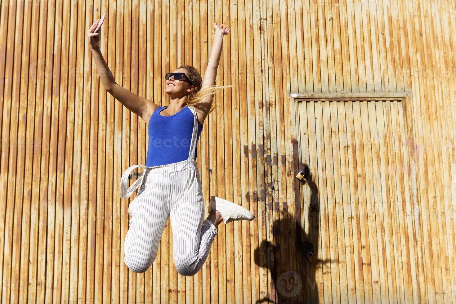 flicka som hoppar medan hon gör en selfie med sin smartphone. foto