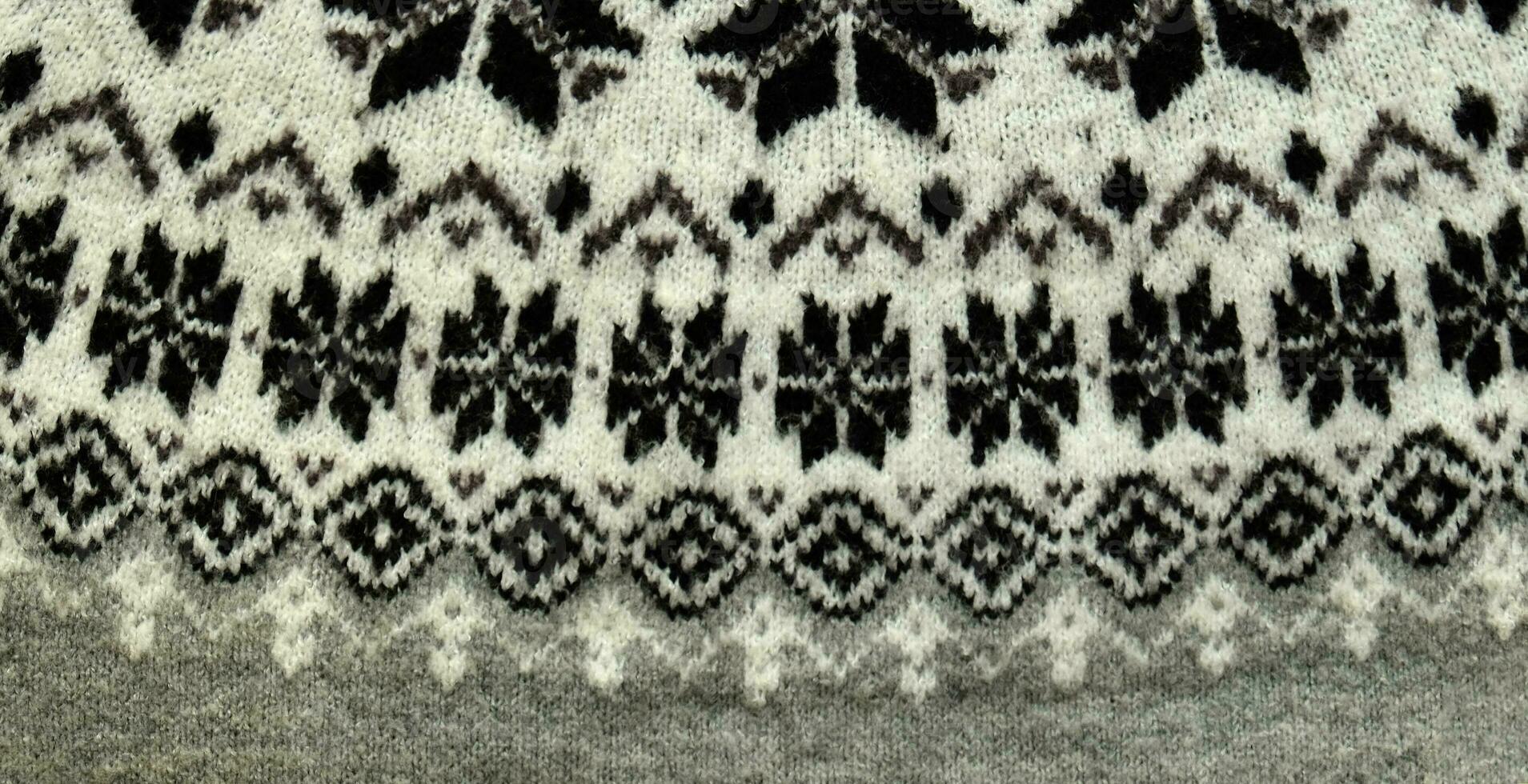 svart och vit vinter- stickat Tröja mönster design med snöflingor. handgjort stickning ull tyg textur. bakgrund av stickning mönster och prydnad. foto