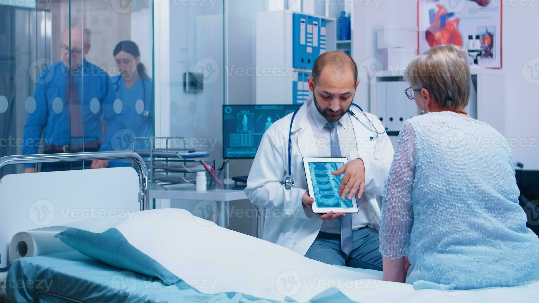 läkare presenter x stråle skanna på digital läsplatta till senior gammal pensionerad kvinna patient vem sitter på sjukhus säng i modern privat klinik. hjärna skärm, smittosam faktor diagnos radiologi foto