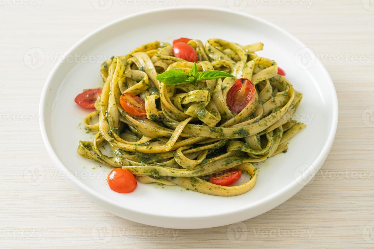 fettuccine spaghetti pasta med pestosås och tomater foto