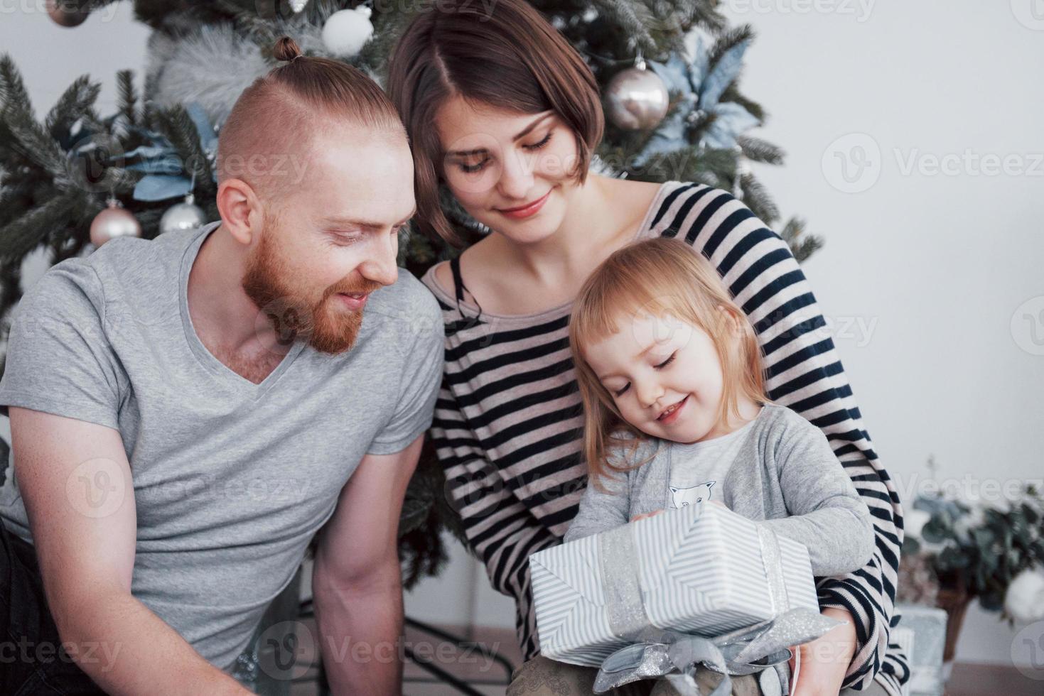 glad familj vid jul på morgonen öppnar presenter tillsammans nära granen. begreppet familjelycka och välbefinnande foto