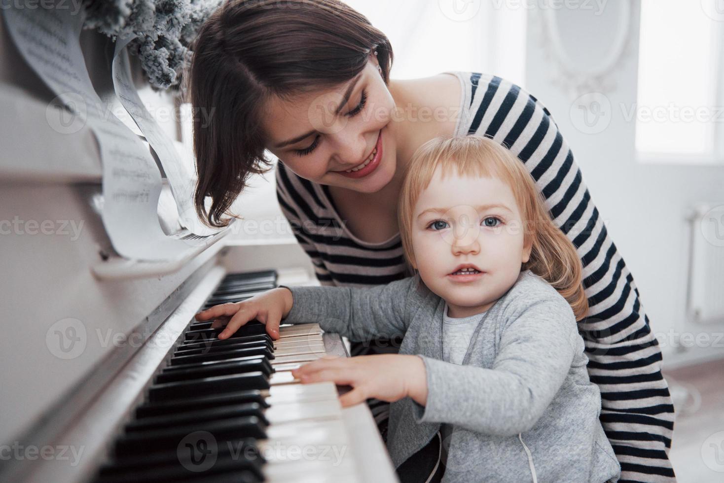 mor och dotter spelar vitt piano, närbild foto