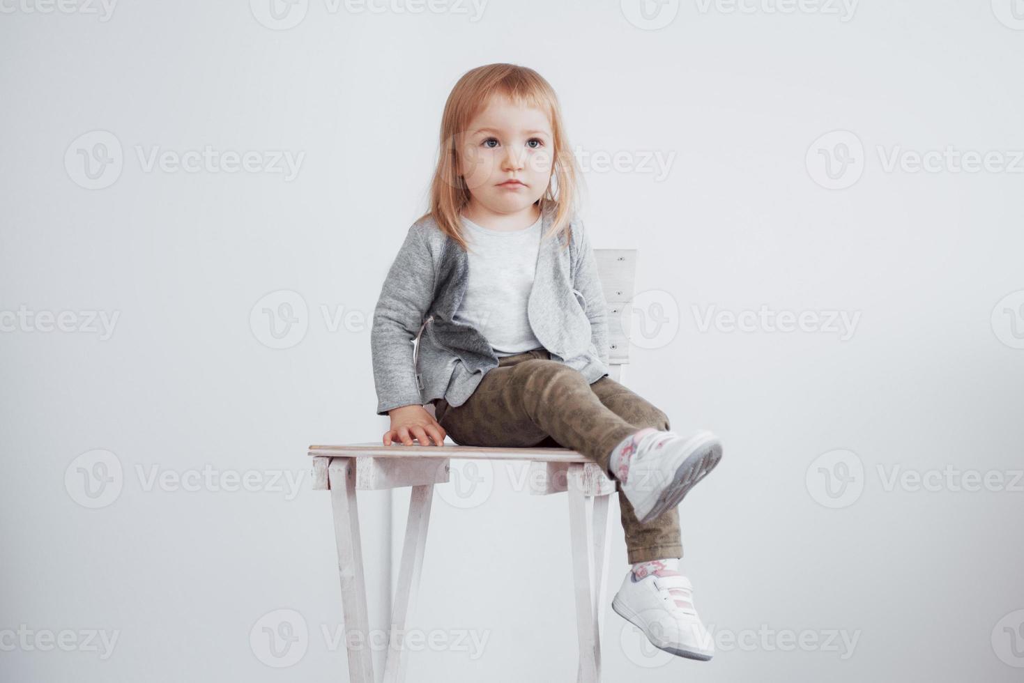 ett litet barn, en liten flicka som sitter på en hög pall och skrattar foto