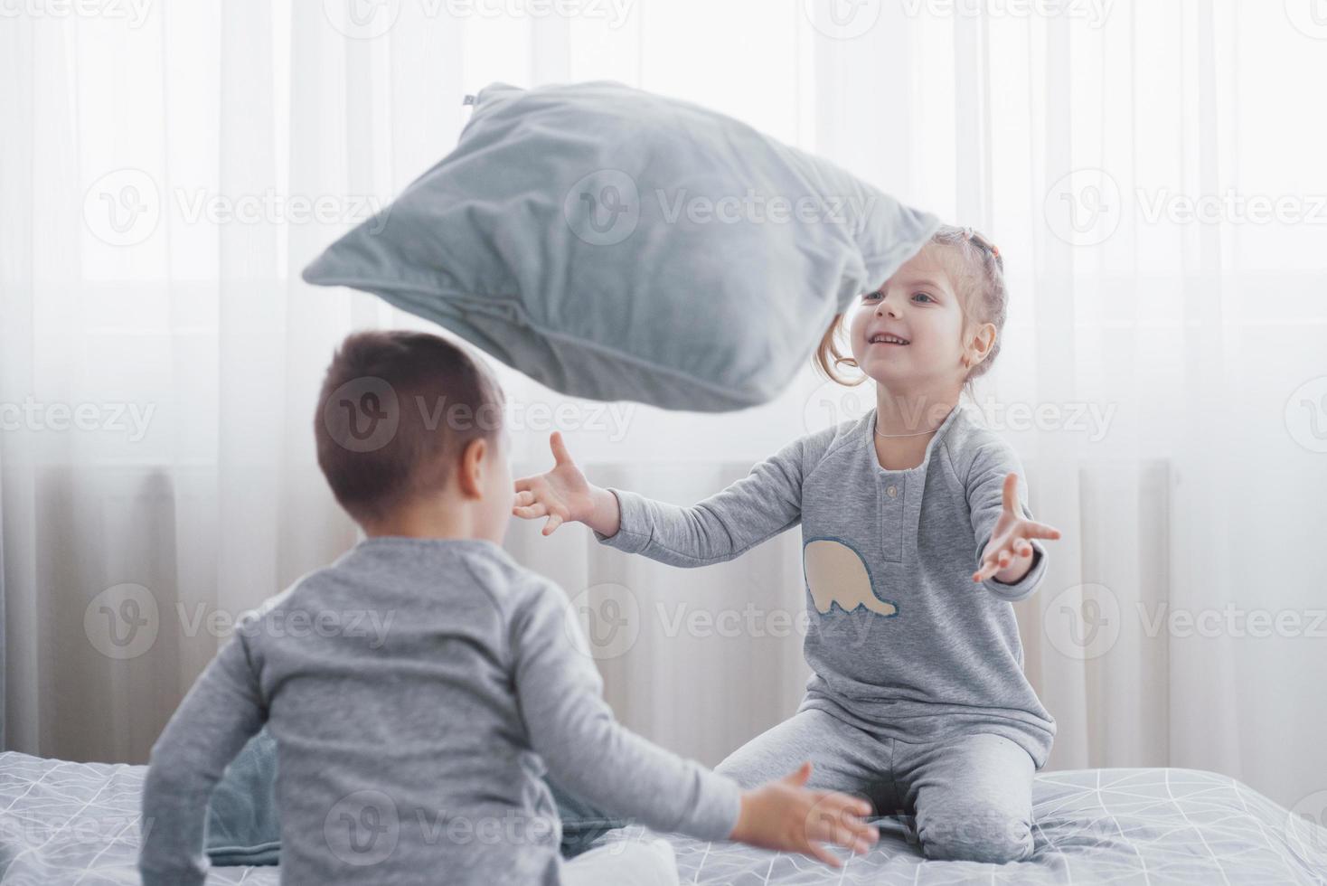 barn i mjuka varma pyjamas som leker i sängen foto