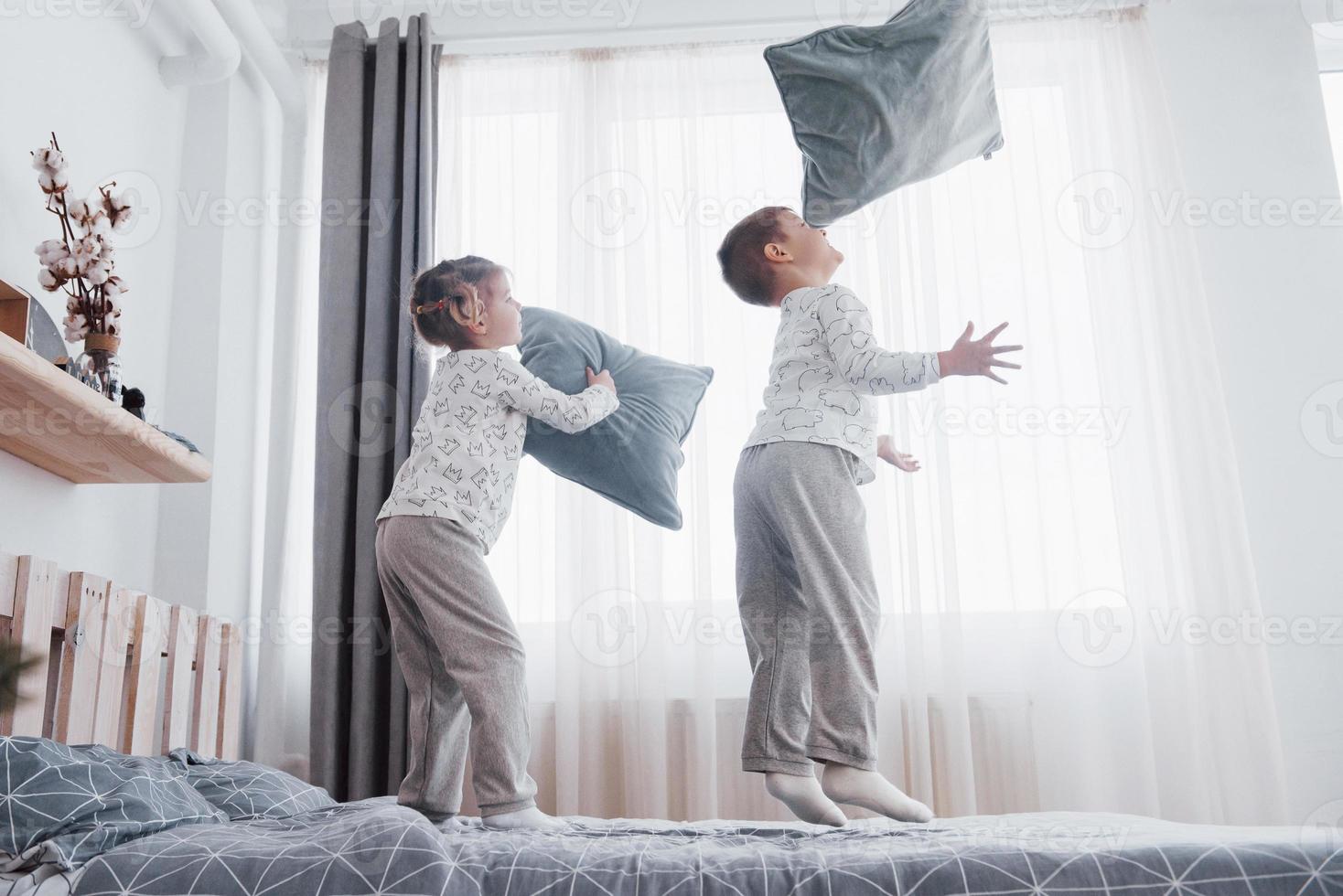 barn i mjuka varma pyjamas som leker i sängen foto