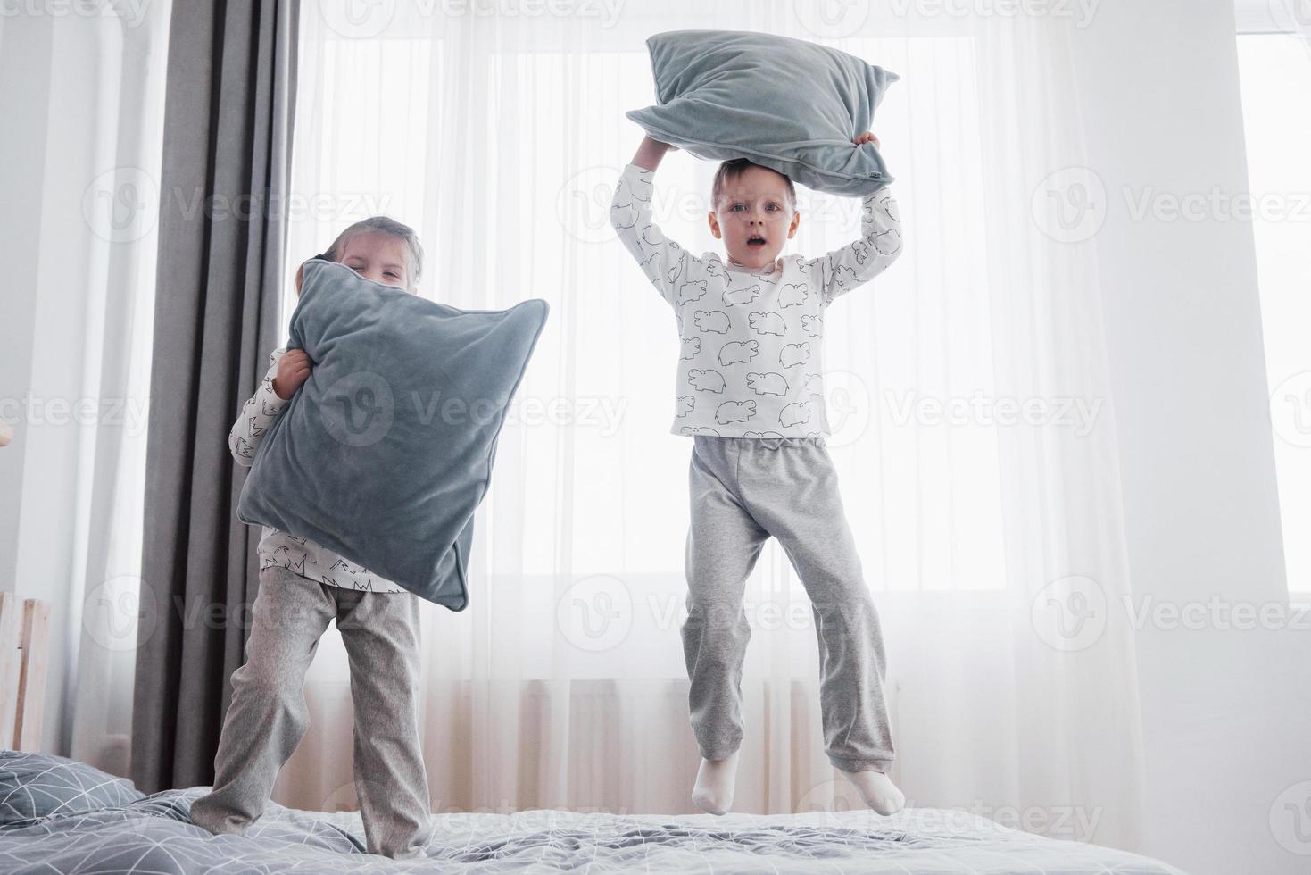 barn i mjuka varma pyjamas som leker i sängen foto