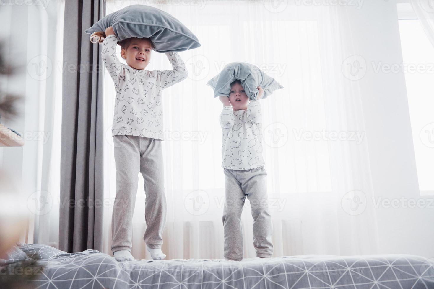 barn i mjuka varma pyjamas som leker i sängen foto