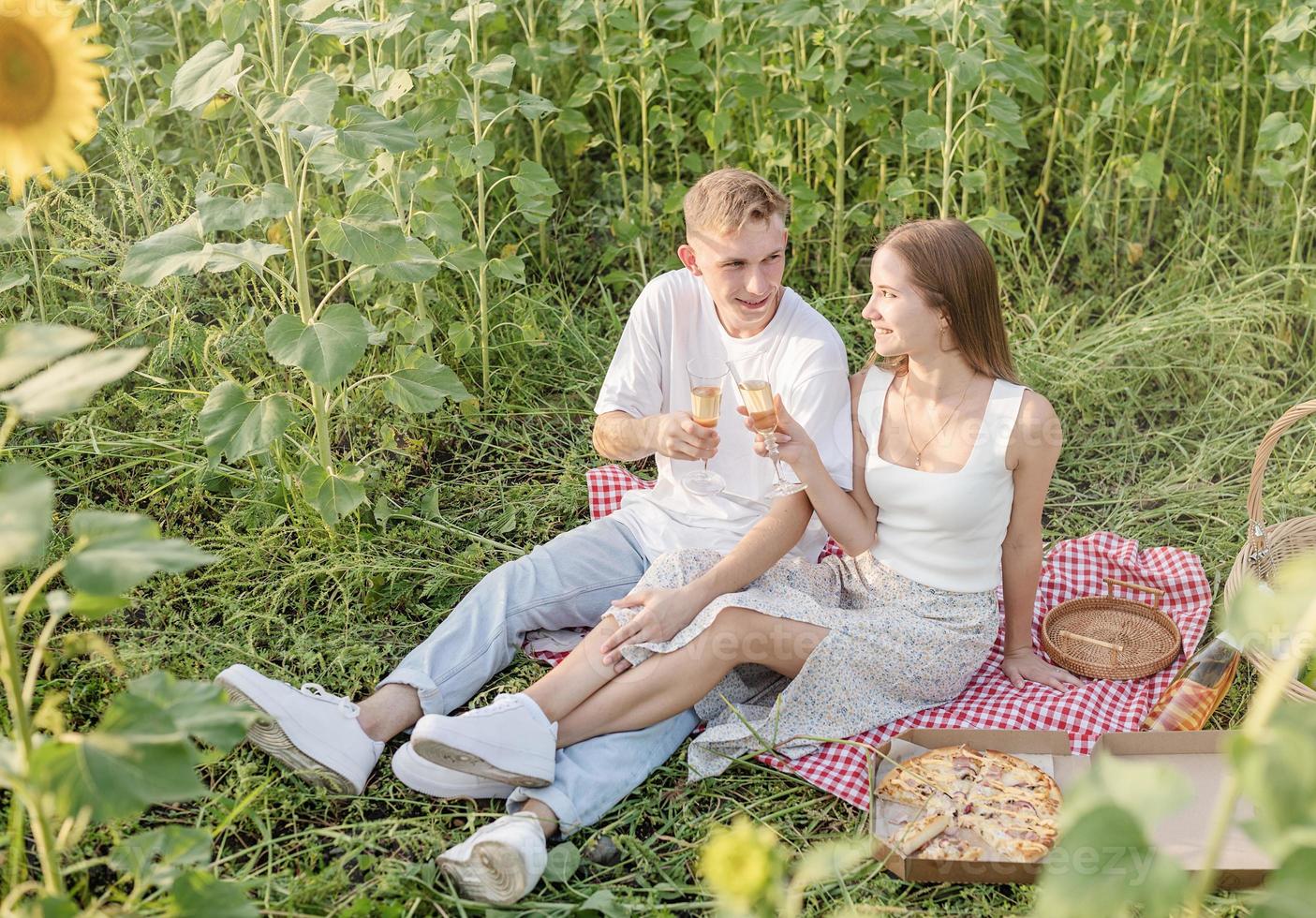 ungt par som har picknick på solrosfältet vid solnedgången foto