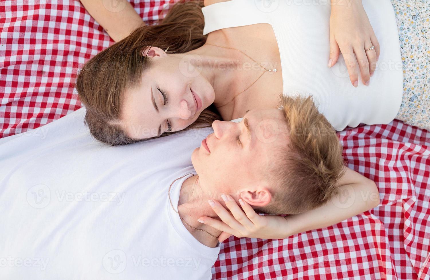ungt par som gosar på en picknickfilt, ovanifrån foto