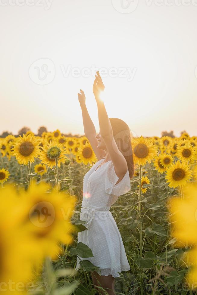 ung vacker kvinna mellan solrosor i solnedgången foto