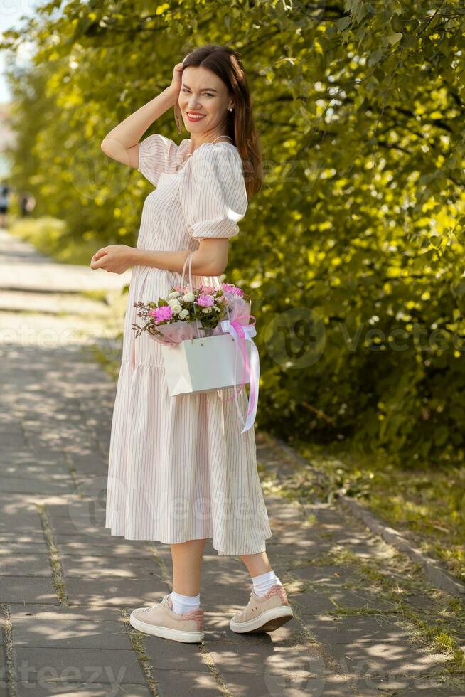 skön flicka med blommor, i en klänning, glasögon och sneakers. foto