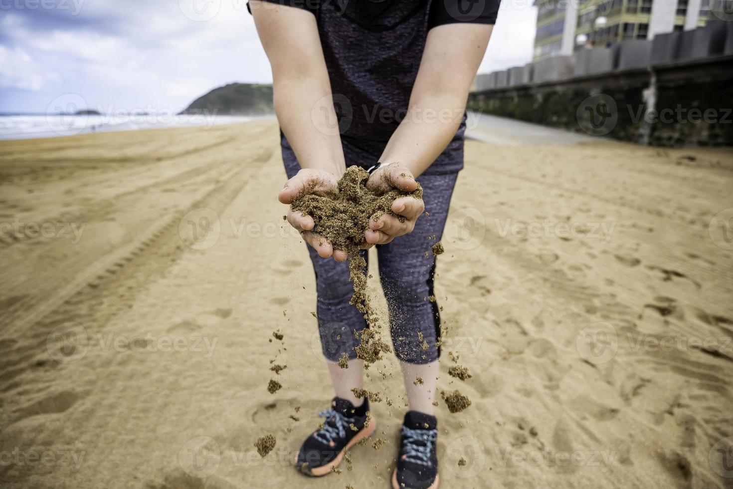 händer som kastar sand på stranden foto