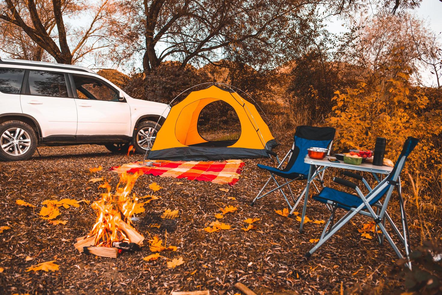 camping höstplats med brasa och bärbara stolar foto