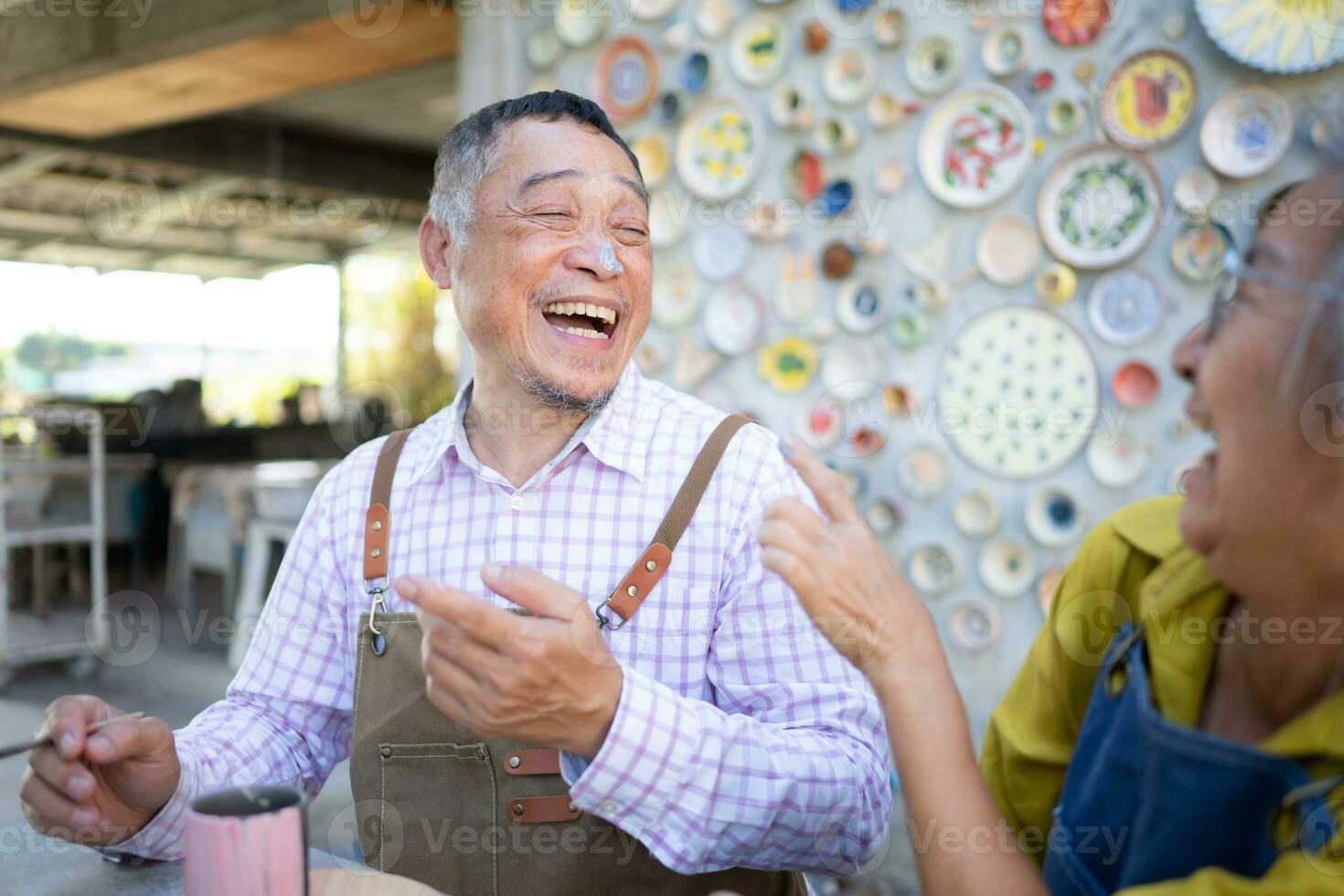 i de krukmakeri verkstad, ett asiatisk pensionerad par är engagerad i krukmakeri framställning och lera målning aktiviteter. foto