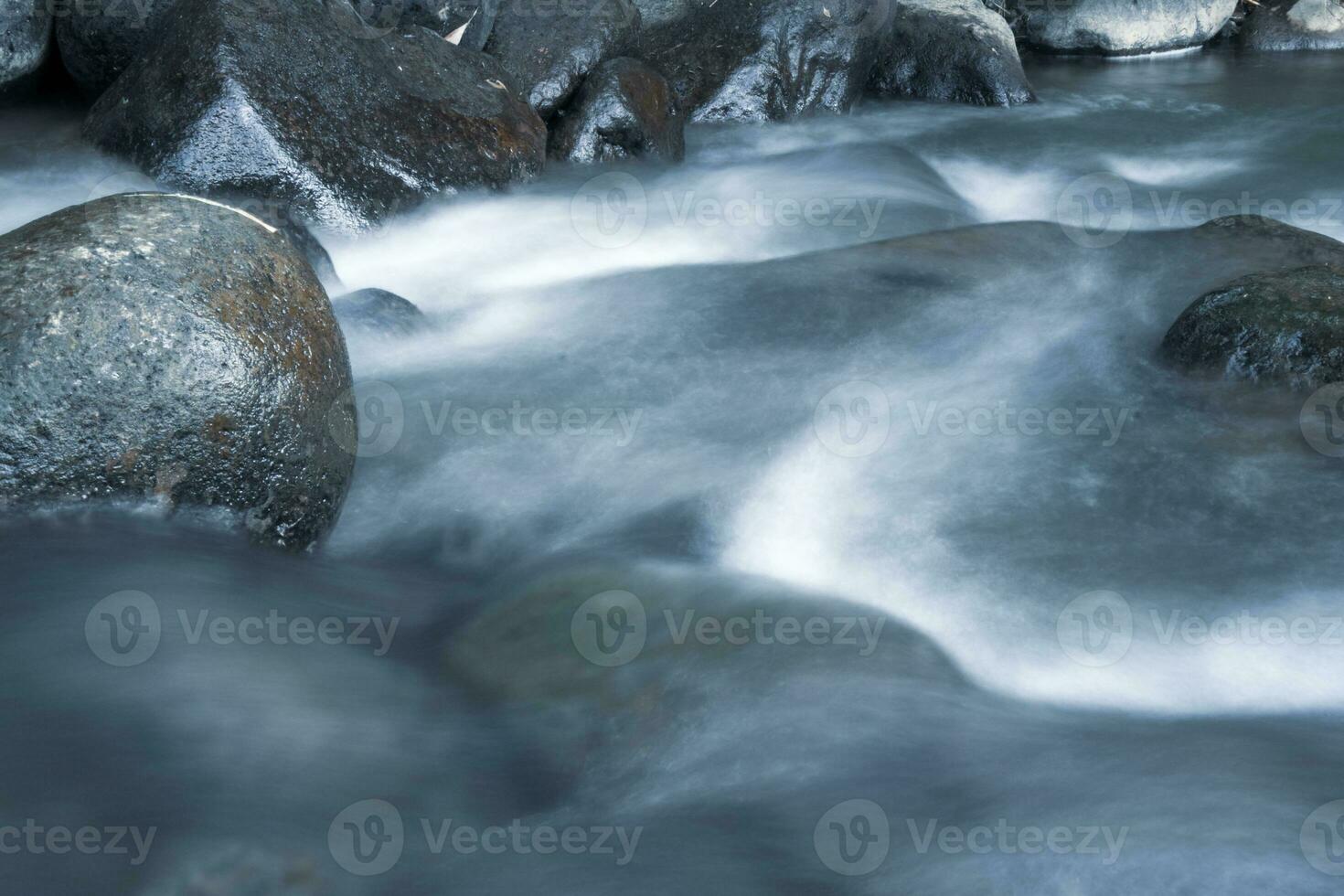 stänga upp av vatten strömmande över kullersten i flod foto