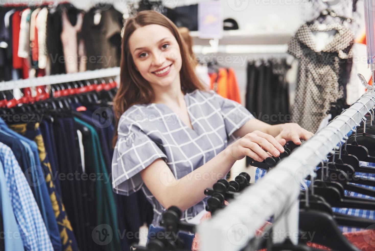 kvinna som handlar kläder. shoppare tittar på kläder inomhus i butik. vacker glad leende asiatisk kaukasisk kvinnlig modell foto