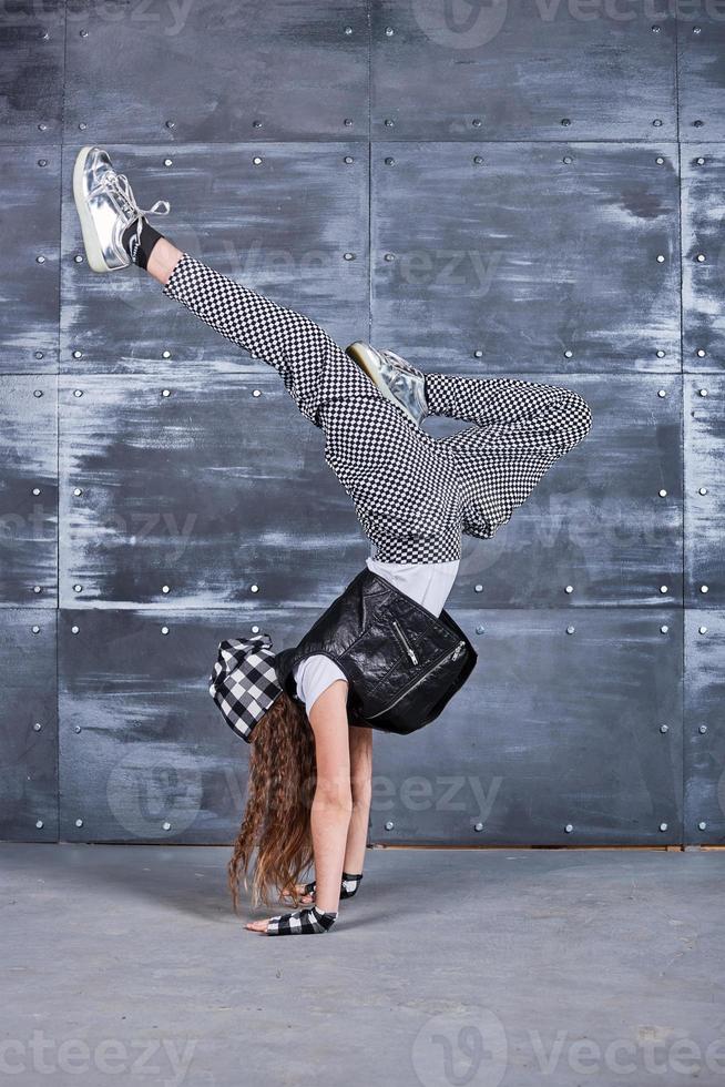 ung vacker flicka som dansar i trendiga kläder på en grungebakgrund foto