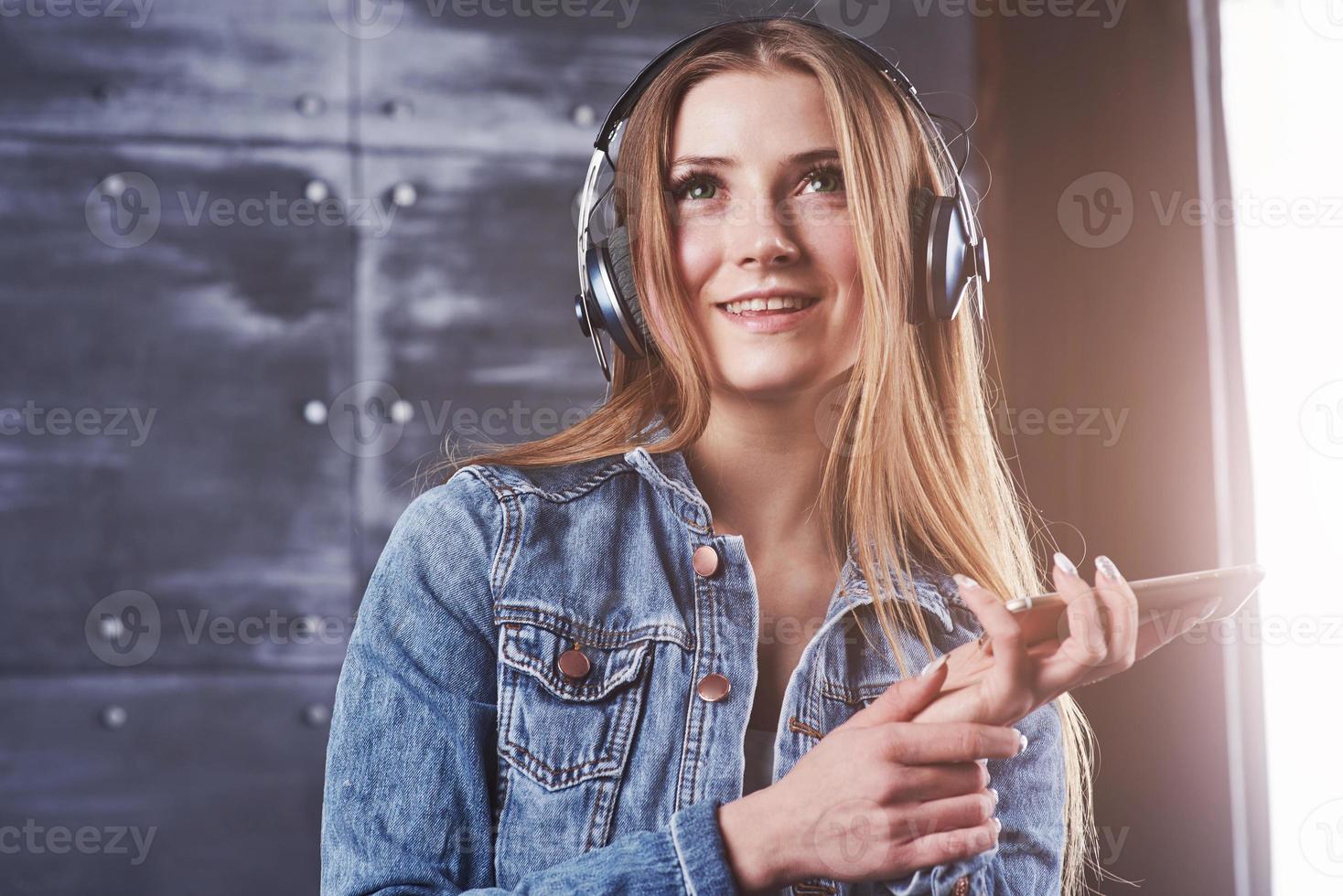 mode, kläder, människor koncept. närbild attraktiv sexig ung kvinna med jeansjacka. flicka poserar i studion lyssnar på musik i hörlurar foto